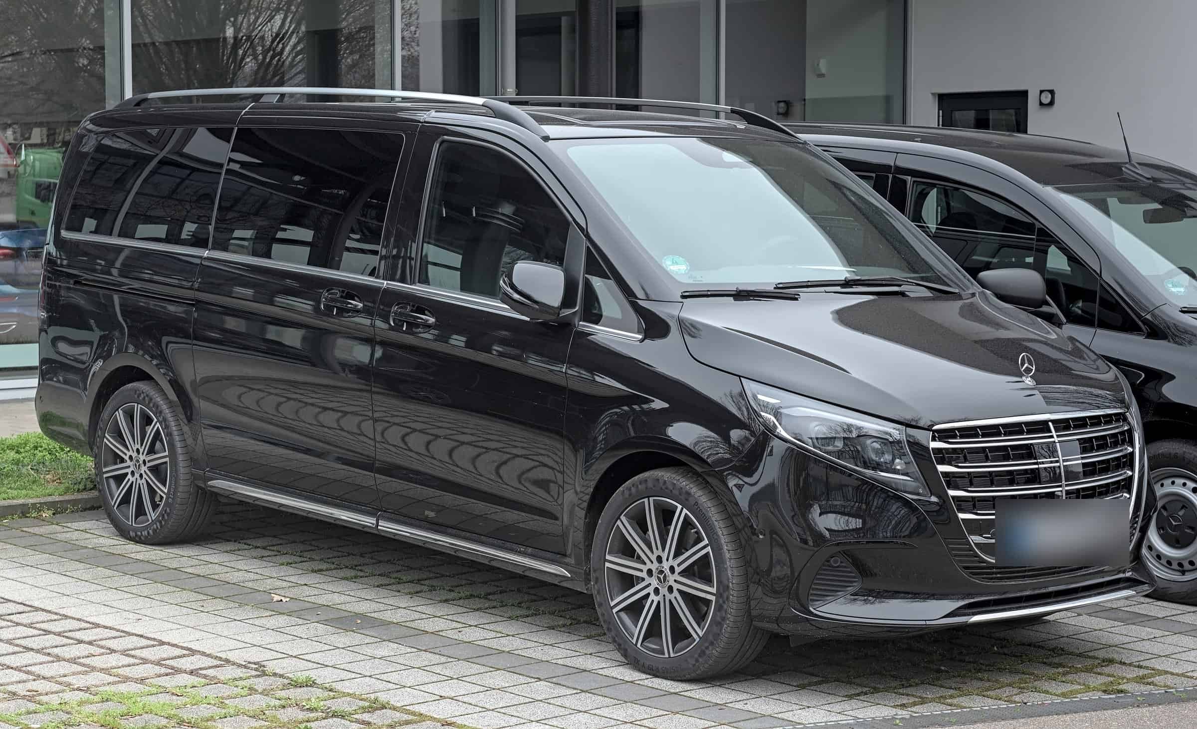 Black Mercedes V-Class in front of a glass office building